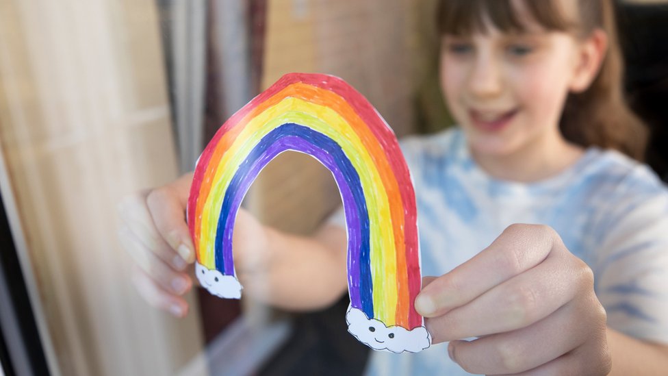 Girl holding a rainbow drawn on a piece of paper