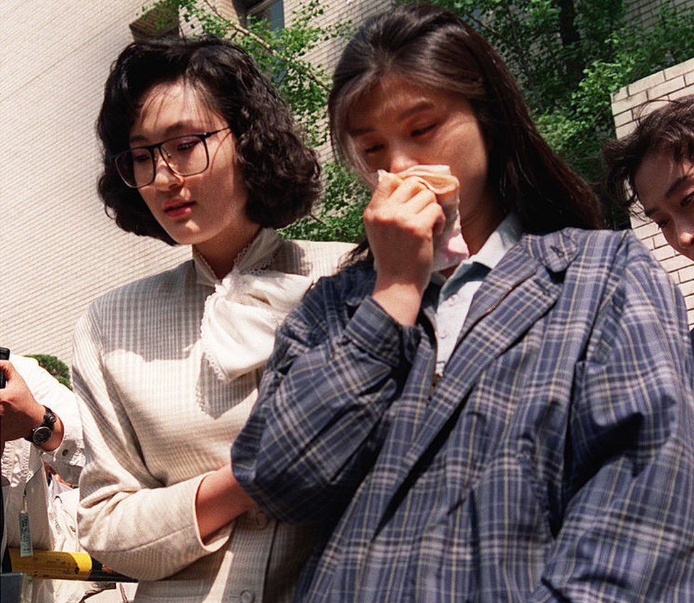 Kim Hyun-hui holds a handkerchief to her nose as she is led from a courtroom in Seoul by a woman investigator, on 25 April 1989