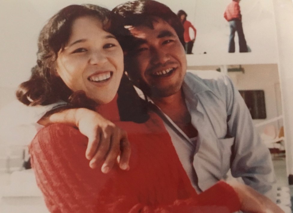 A picture showing Teruaki Masumoto as a young man, with an arm round his sister. Both of them are laughing