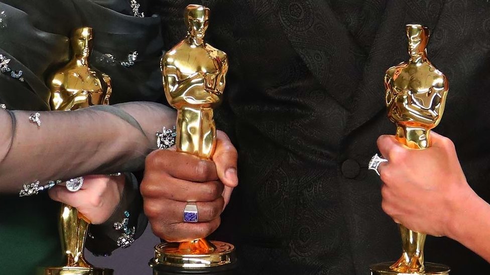 Close-up of Oscar statuettes in people's hands