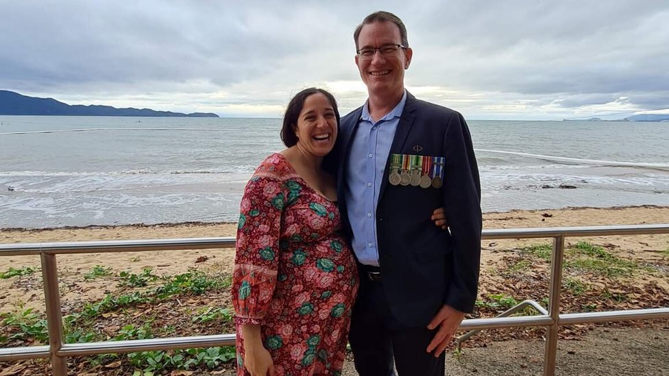Melissa and Mez stand together in front of beach