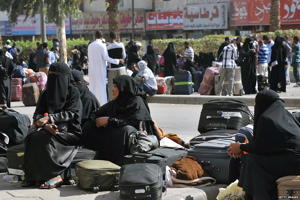Foreign workers wait with their belongings before boarding police buses in Riyadh