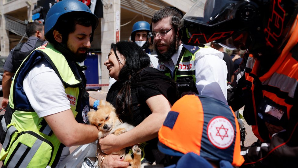 Israeli medics help a woman after a rocket hit a shopping centre in Ashkelon, southern Israel (11 May 2021)