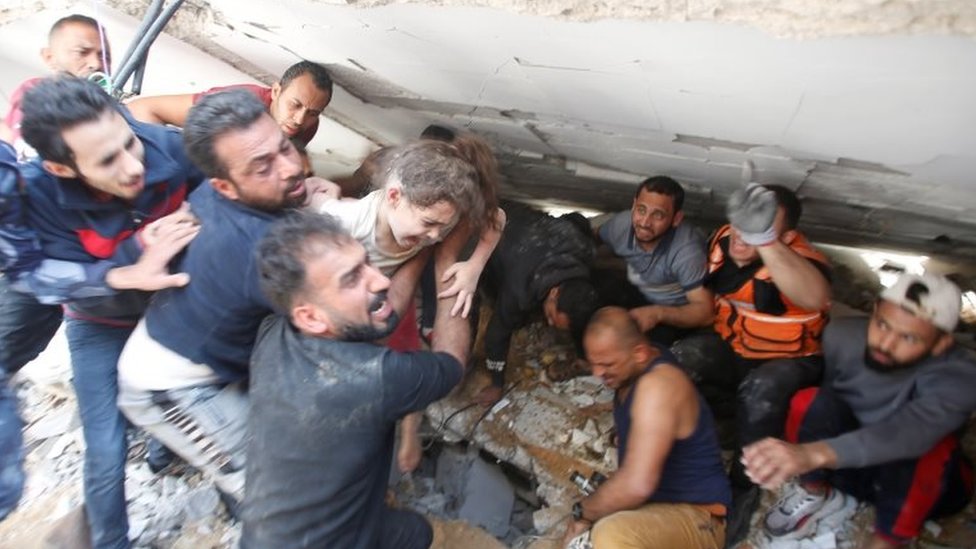 Rescuers carry a girl as they search for victims amid rubble at the site of Israeli air strikes, in Gaza City May 16, 2021