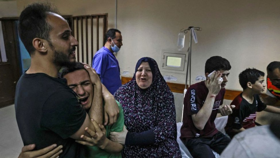 A member of the Abu Dayer family, surrounded by relatives, cries at the Al-Shifa hospital after the death of his father and cousin in an Israeli air strike