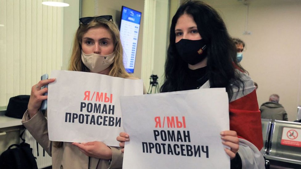 Devuški v aэroportu Minska s plakatami v podderžku Romana Protaseviča
