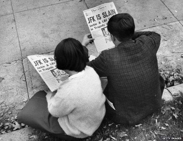 Two people in Lafayette Park, Washington, reading the newspaper reports of President John F Kennedy's assassination