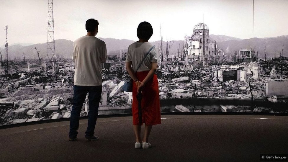 Hirošima i Nagasaki: Može li nuklearni rat biti moralno opravdan 1 dvoje ljudi ispred slike rusevina