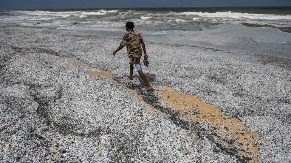 A man walks amid debris washed ashore from the X-Press Pearl on 29 May