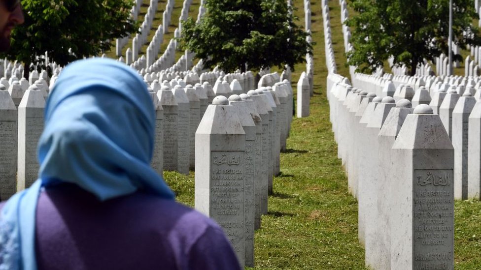 A woman stands near tombstones at a cemetery to honour the victims of the 1995 Srebrenica massacre