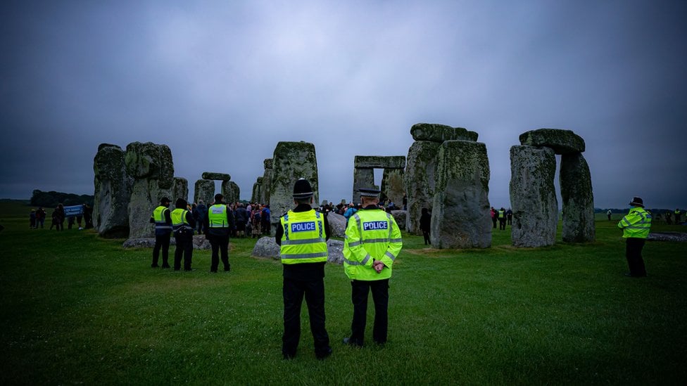 Police watch crowds celebrate during Summer Solstice at Stonehenge, where some people jumped over the fence to enter the stone-circle to watch the sun rise at dawn of the longest day in the UK.