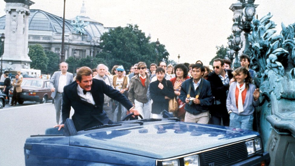 Film i zabava: Francuske lokacije u romanima o Džejmsu Bondu imaju dozvolu da nas uzbude 9 In this scene from the film of A View to a Kill, Roger Moore as Bond clambers out of a wrecked Renault car