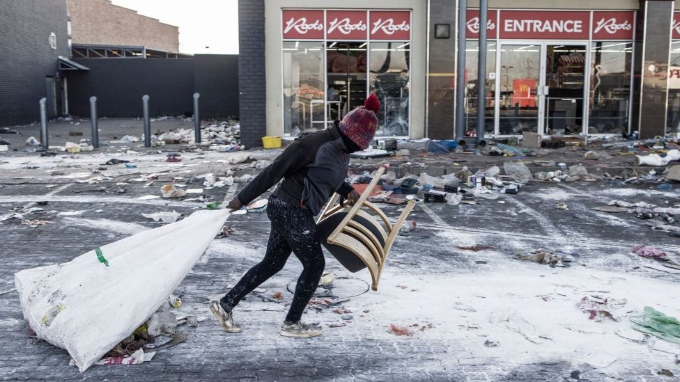 Neredi u Južnoj Africi: Zašto je jedna mama morala da baci bebu neznancima 2 A suspected looter pulls a few items along the ground outside a vandalised mall in Vosloorus, on the outskirts of Johannesburg,