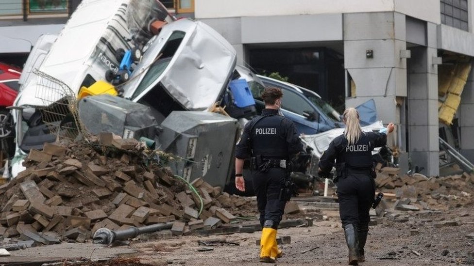 Police walk past debris in the spa town of Bad Neuenahr