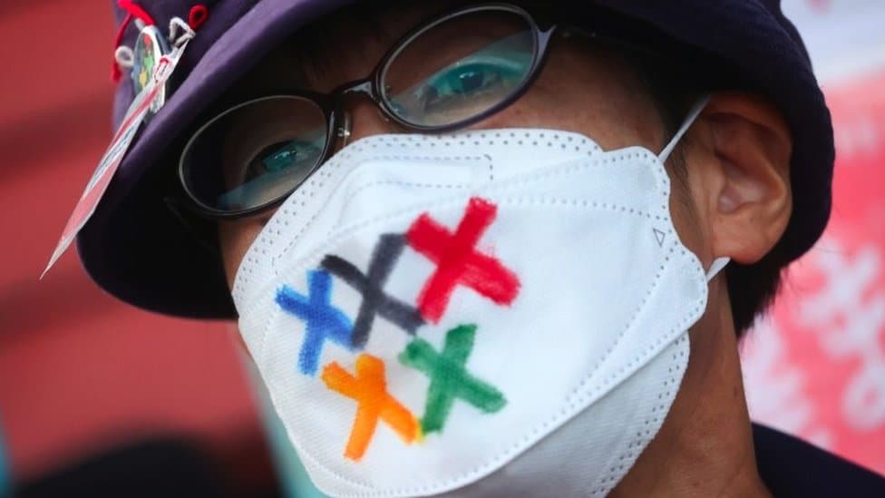 Korona virus i Olimpijske igre: Mogu li vlasti u Japanu da spreče da manifestacija postane „događaj super širenja zaraze“ 1 A man wears a facemask with Olympic colours on it protesting against the Games