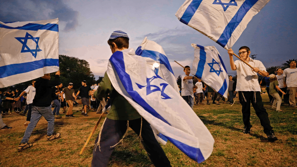 Children wave Israeli flags during a gathering in the settlement of Mehola in the occupied West Bank