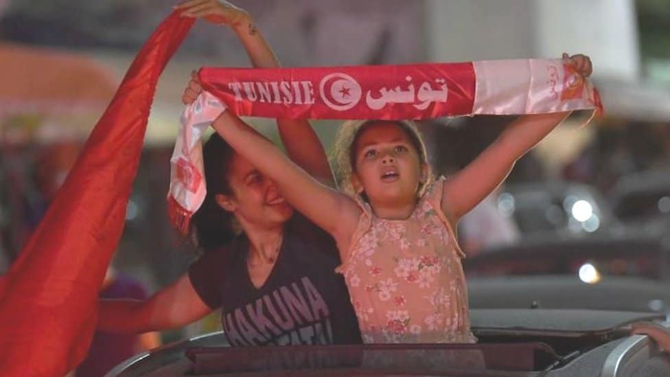 A little girl holds a scar with the Tunisian flag during a protest in Tunis