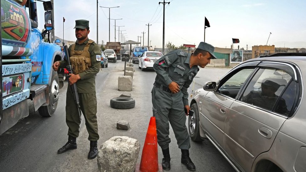 Afghan police stand guard at a checkpoint along the road in Kabul on August 14, 2021