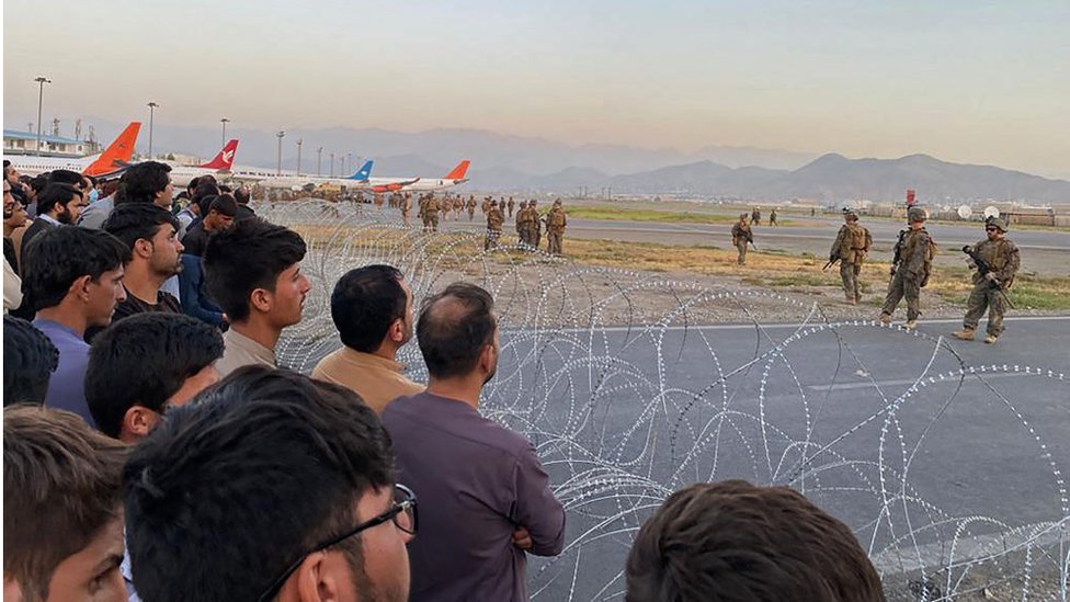 Avganistanci stoje ispred žičane ograde oko piste na aerodromu u Kabulu, avgust 2021