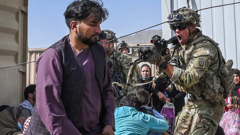 A US soldier (C) point his gun towards an Afghan passenger at the Kabul airport in Kabul on 16 August 2021.