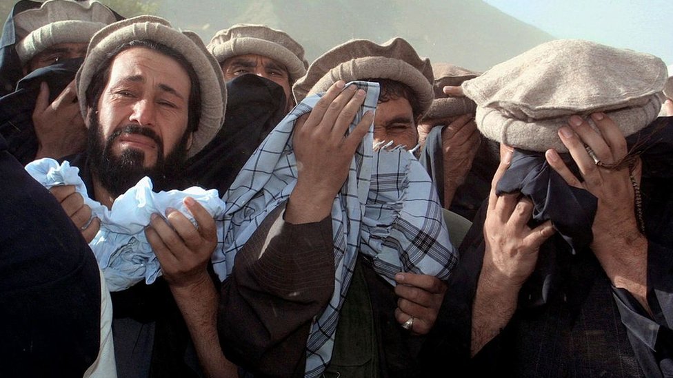 Afghan men crying at a funeral ceremony