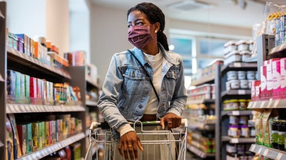 A black young woman pushing a trolley at a supermarket