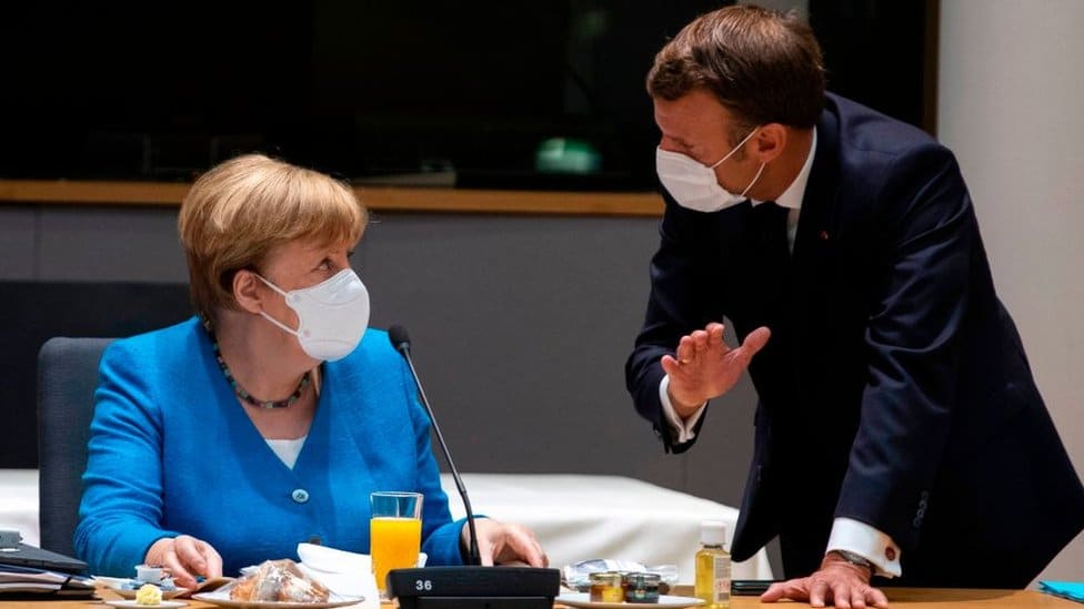 Germany's Chancellor Angela Merkel (L) talks with France's President Emmanuel Macron prior the start of the EU summit at the European Council building in Brussels, on July 18, 2020