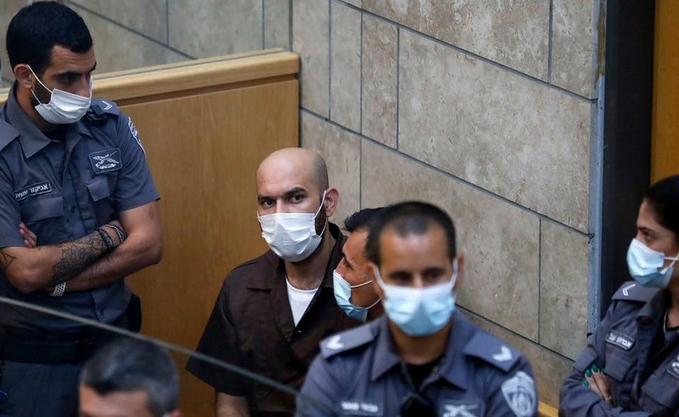 Palestinian Ayham Kamamji, 35, is surrounded by Israeli police officers as he appears at the magistrates' court in the northern Israeli city of Nazareth, on September 19, 2021