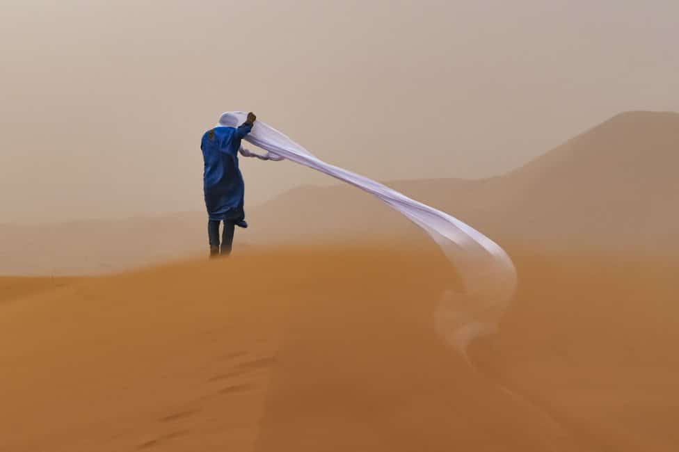 Čoveku vetar odnosi maramu koju je nosio oko glave dok je bio u pustinji Sahari