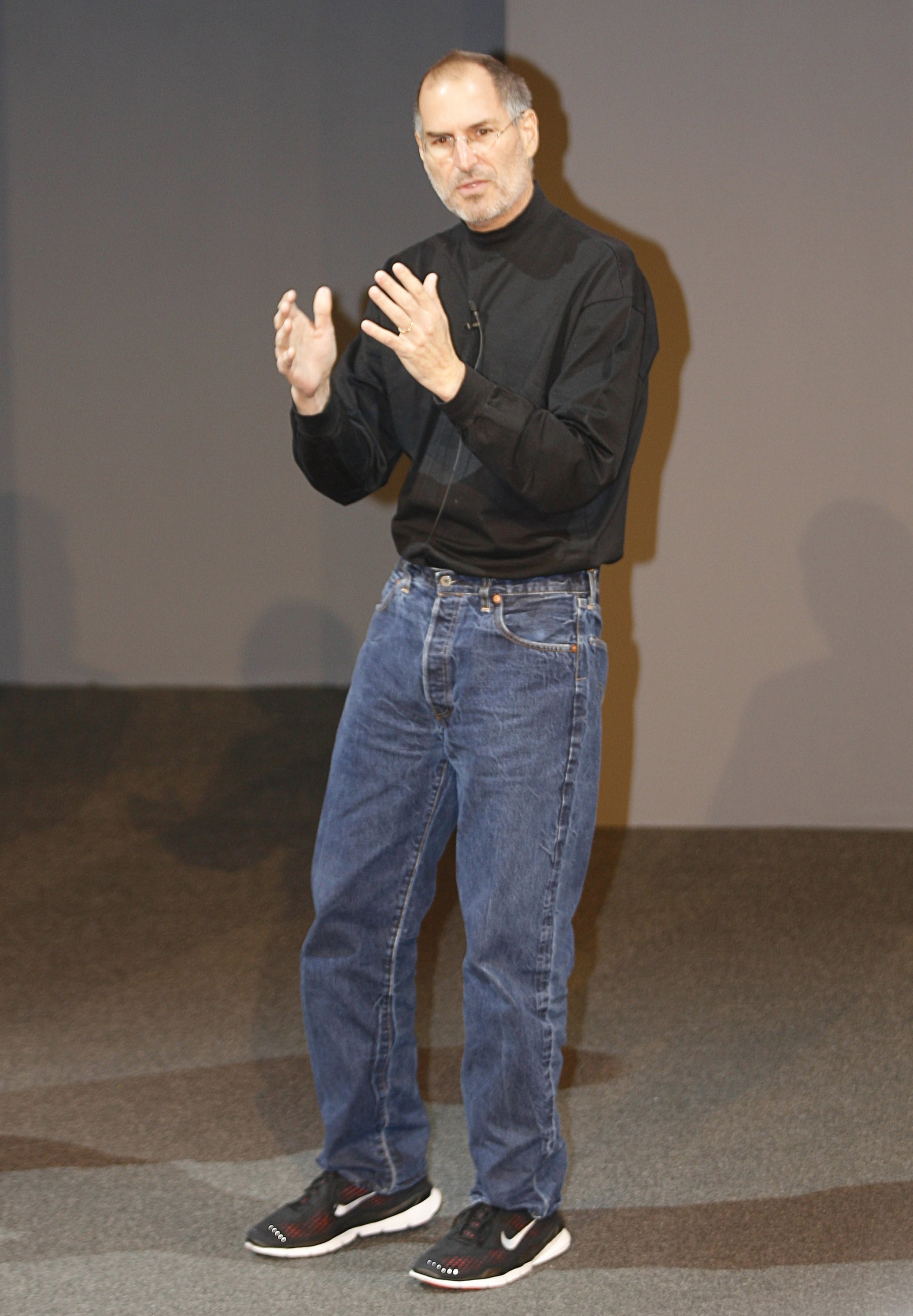 Steve Jobs wearing a black turtleneck sweater, blue jeans and sports shoes at Apple events