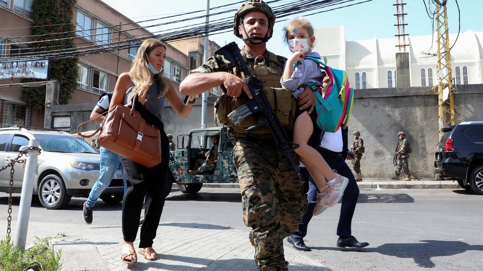 A Lebanese army soldier carries a schoolchild after gunfire erupts during protest against the judge investigating last year's blast at the city's port (14 October 2021)