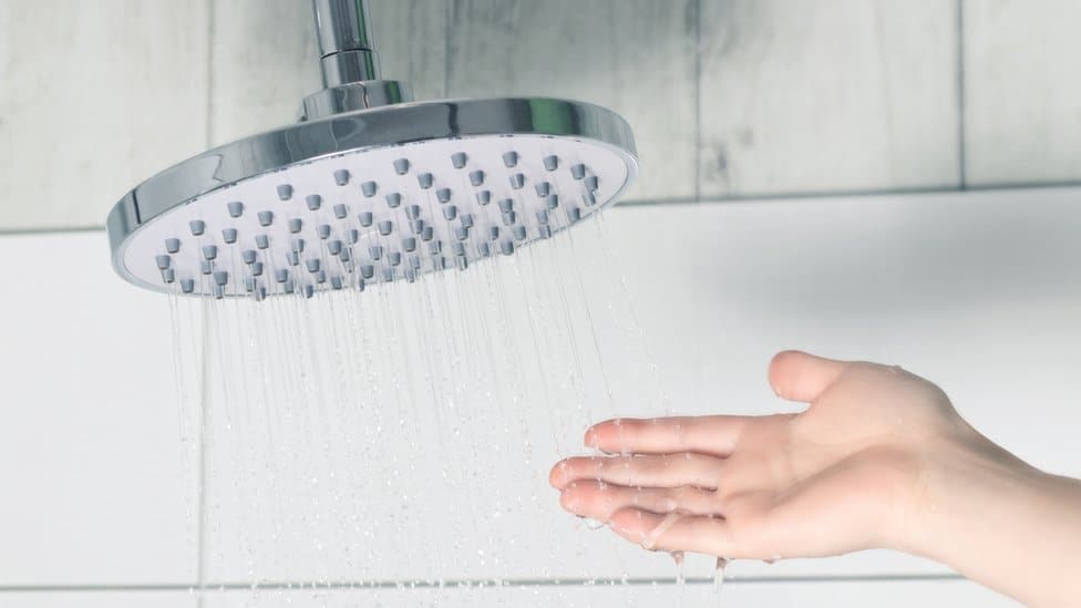 Mão experimentando a água do chuveiro