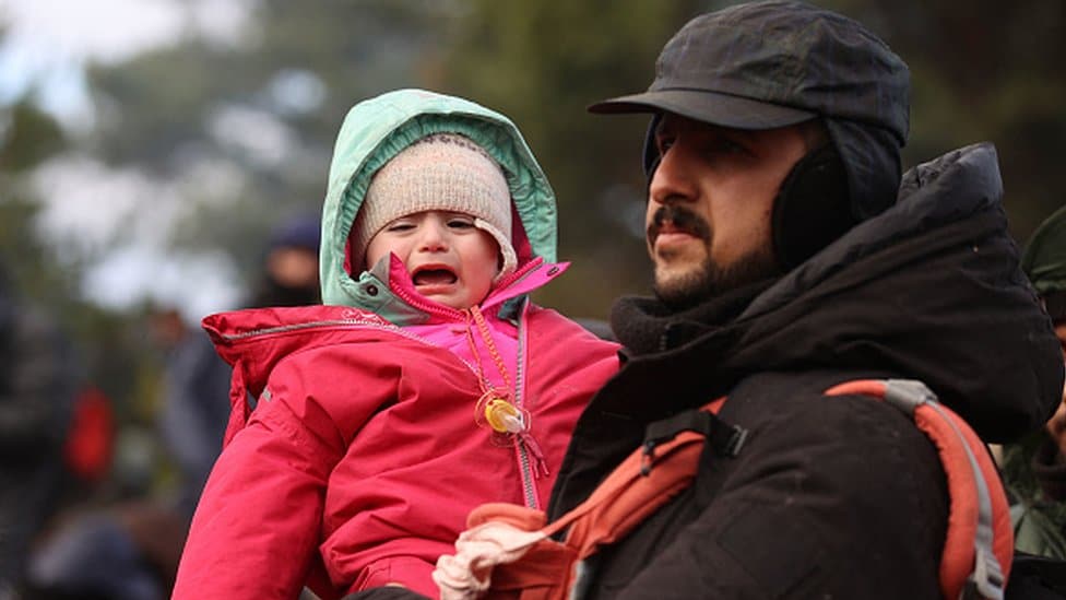 Migranska kriza u Evropi: Napetosti na poljsko-beloruskoj granici splase, migranti na toplom u privremenom skloništu 12 A man holds his child on the Poland-Belarus border