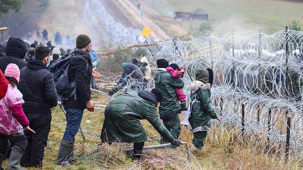 Migranti, Belorusija i Poljska: Stotine migranata na granici Belorusije i Poljske, Varšava strahuje od „oružane eskalacije" 5 Migrants stand near a barbed-wire fence