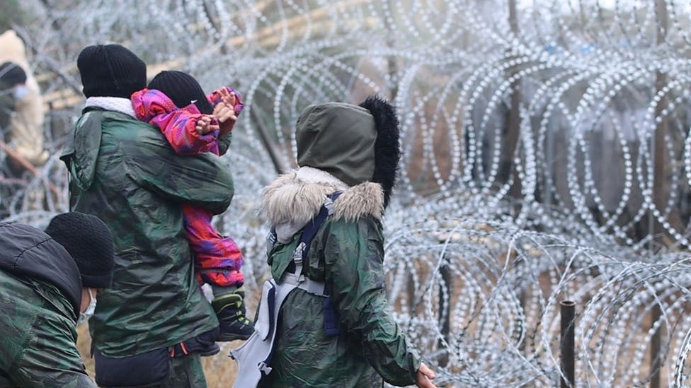 Migrants at a barbed wire fence at Belarus' border with Poland