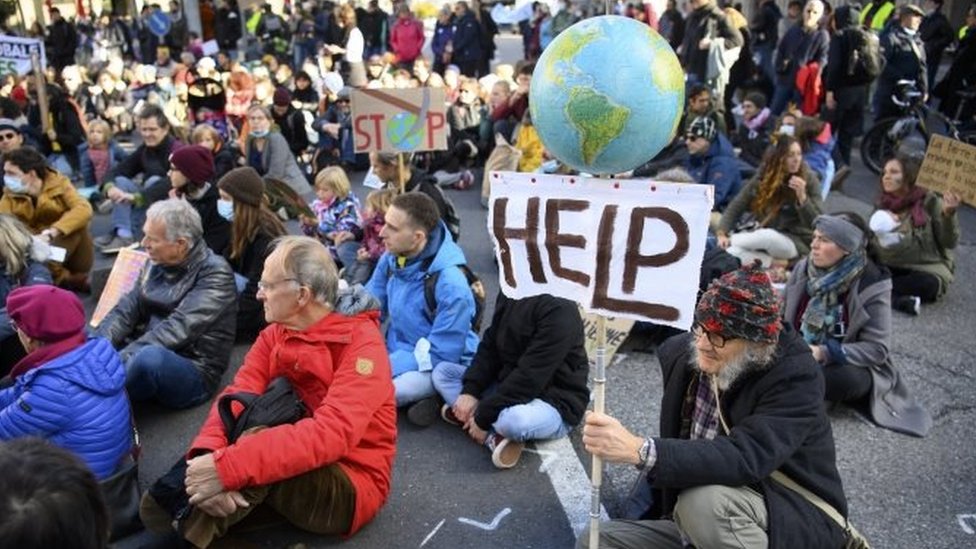 A protester holds a globe and a slogan that reads "Help" during a rally in Lausanne, Switzerland. Photo: November 2021