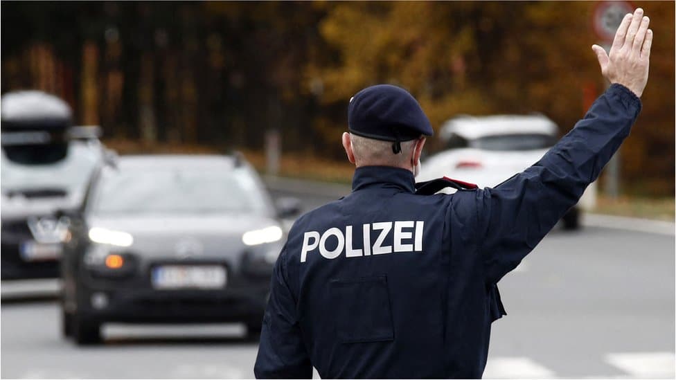 Korona virus i Austrija: Kako dijaspora živi pod novim merama - „Beč je podeljen grad na vakcinisane i nevakcinisane" 3 An Austrian police officer gestures towards car drivers at a traffic control point in Klagenfurt, Austria