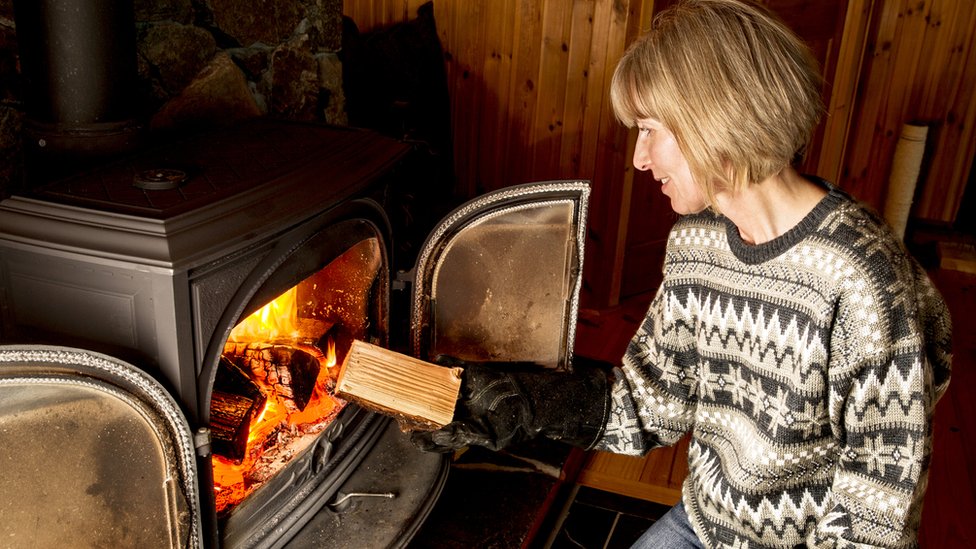 Woman putting log in stove