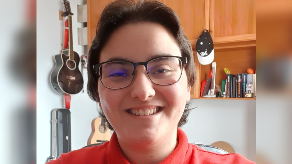 Transrodni ljudi i autizam: Kad se autistični i rodni identitet preklope 4 Daniel smiles at the camera. They are wearing glasses and a red top.