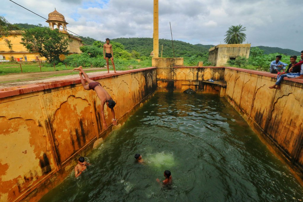 Children jump into a step-well (baori) after it was filled with rain water, near Man Sagar Lake in Jaipur, Rajasthan, India