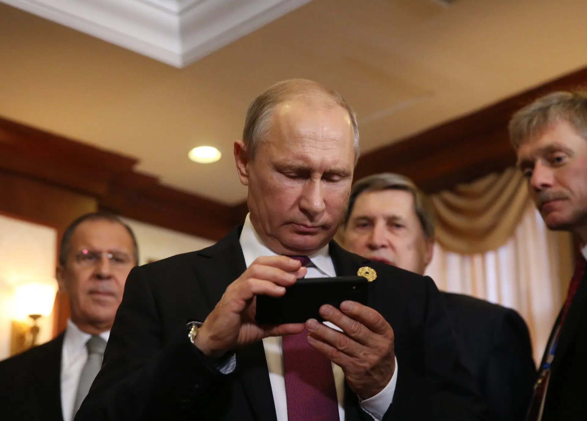 Rusija, Putin i internet: Država pokušava da cenzuriše zapadne društvene mreže 1 Vladimir Putin examines an iPhone in the company of spokesman Dmitri Peskov (right) and Foreign Minister Sergei Lavrov (left)