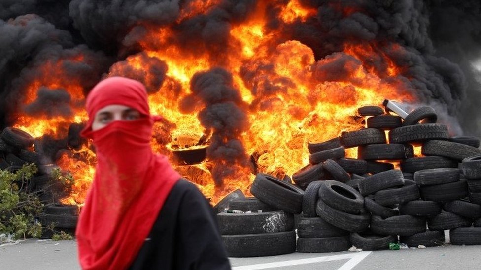 A protester stands in front of blazing tyres in Montegro