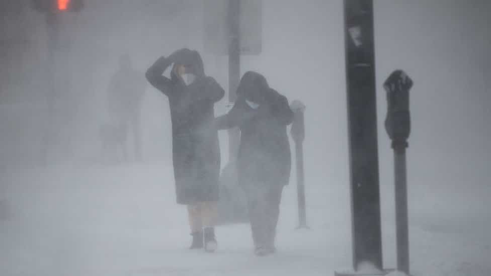 Amerika i vremenske nepogode: Istočnu obalu zahvatila snežna oluja, hiljade bez struje, stručnjaci upozoravaju na bombogenezu 1 People protect themselves from blowing wind and snow during white-out conditions as Winter Storm Kenan