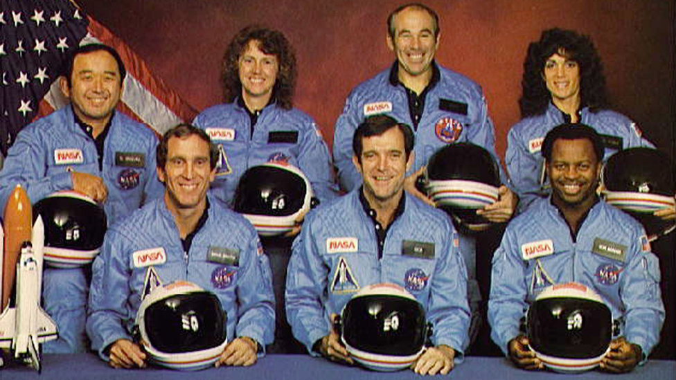 Space Shuttle Challenger crew members gather for an official portrait November 11, 1985 in an unspecified location. (Back, L-R) Mission Specialist Ellison S. Onizuka, Teacher-in-Space participant Sharon Christa McAuliffe, Payload Specialist Greg Jarvis and mission specialist Judy Resnick. (Front, L-R) Pilot Mike Smith, commander Dick Scobee and mission specialist Ron McNair.