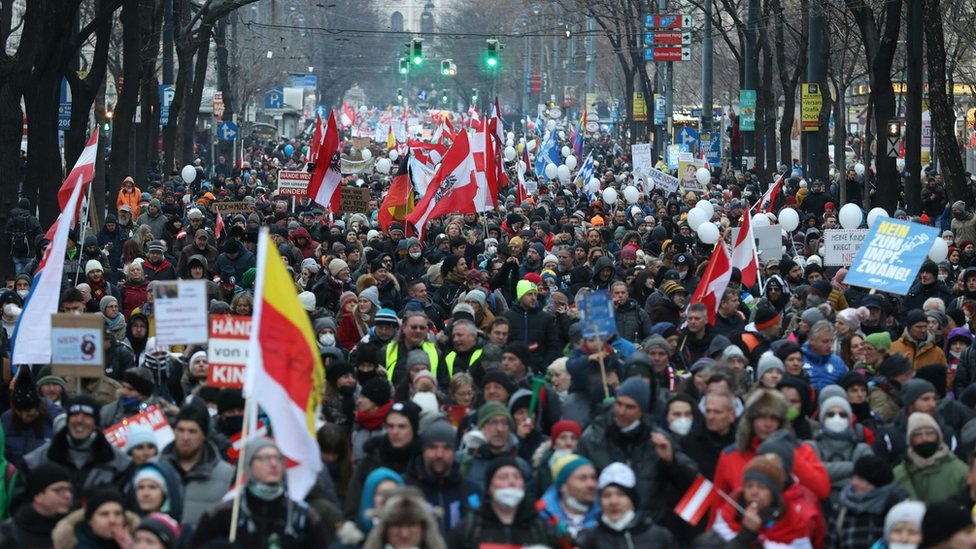 Menschen tragen österreichische Fahnen, als sie am 8. Jänner gegen die Covid-Maßnahmen der österreichischen Regierung demonstrieren