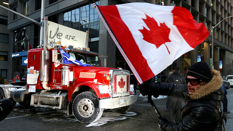 Korona virus. Kanada i Francuska: Vlasti u Parizu zabranile Konvoj slobode, vanredno stanje u kanadskoj pokrajini Ontario 10 A person waves a Canadian flag in front of a truck