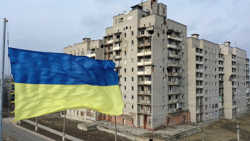 A flag of Ukraine flies in front of a building, damaged in the clashes between Ukrainian army and pro-Russian separatists, is seen as diplomatic efforts to resolve the Ukraine-Russia crisis continue on February 17, 2022, in Avdiika, Donetsk.