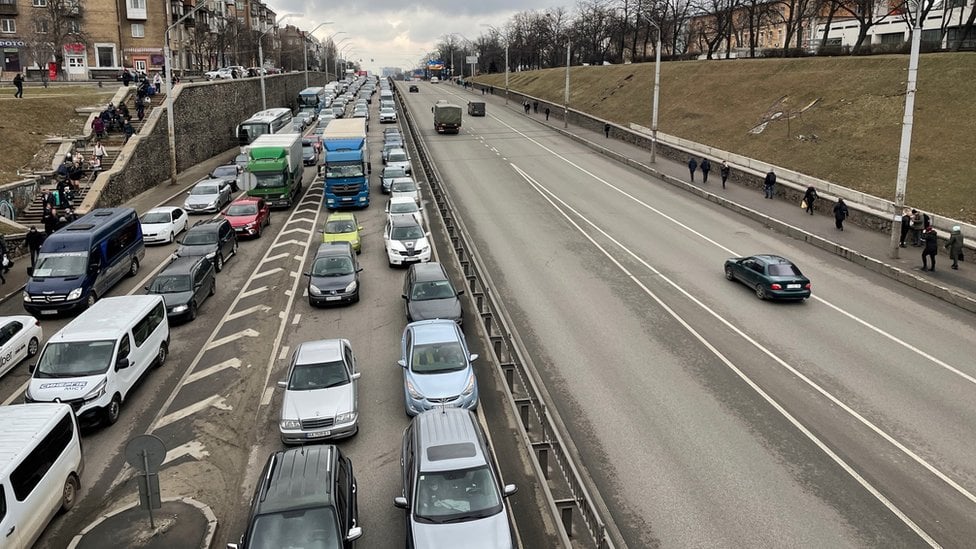 Four lanes of traffic are completely filled by a traffic jam in one direction, while the other direction is virtually empty