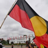 n indigenous protesters holds a flag in front of Old Parliament House, marking the 50th anniversary of The Aboriginal Embassy, in Canberra, Australia