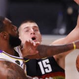 LeBron James (L) shoots past defending Denver Nuggets center Nikola Jokic